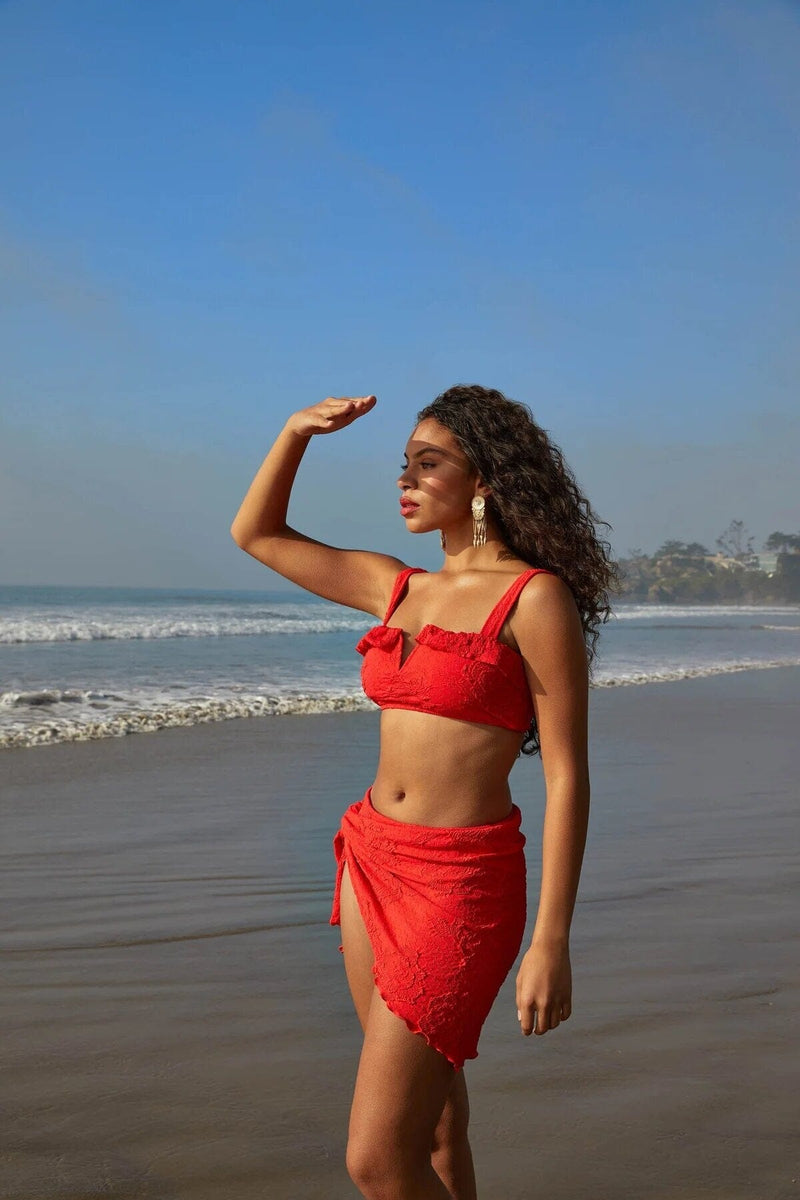 A model wearing a red bikini and sarong on the beach