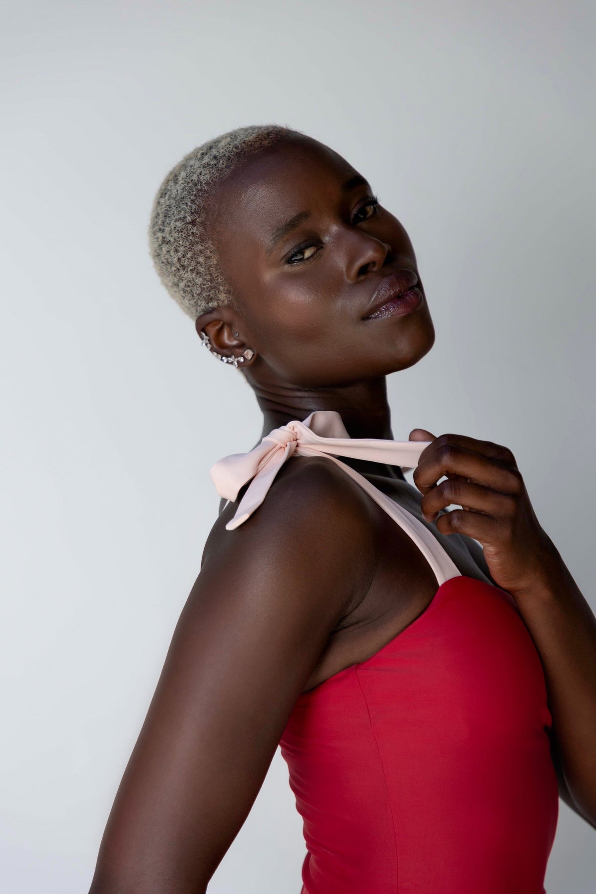 a model adjusting the strap of a red one-piece swimsuit