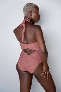 a model facing away from the camera in a brown halter one-piece