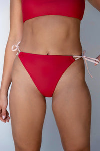 a model in red bikini bottoms with pink ties