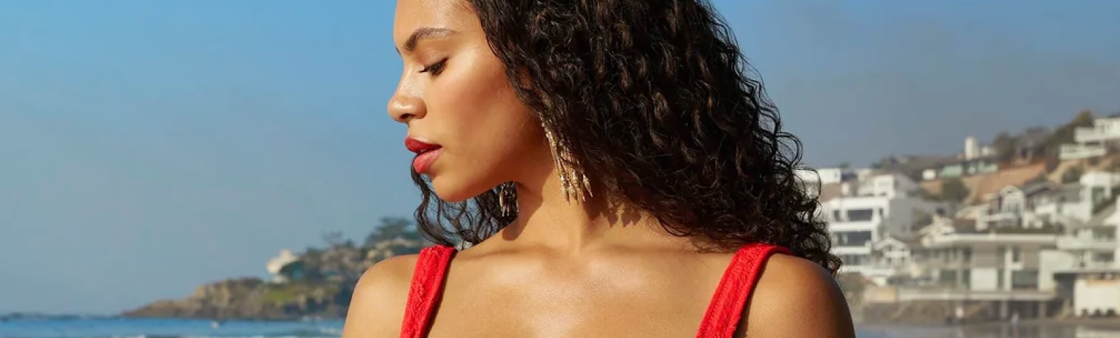 a model on the beach in a red high-waisted bikini with ruffle detail